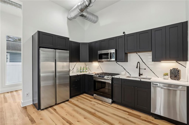 kitchen with stainless steel appliances, light countertops, a sink, and a towering ceiling