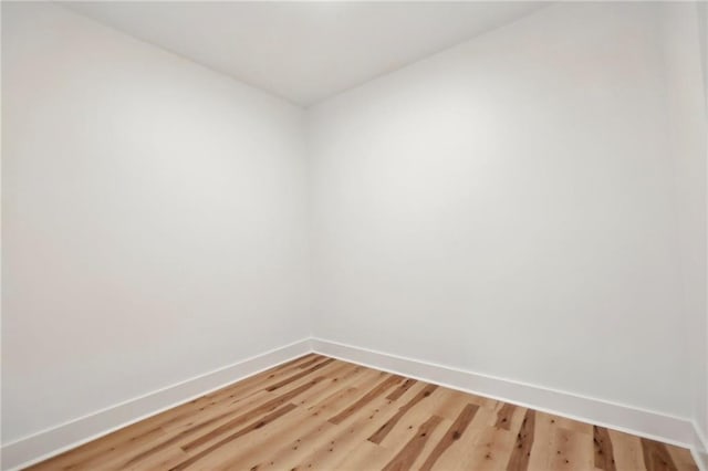 spare room featuring baseboards and light wood finished floors