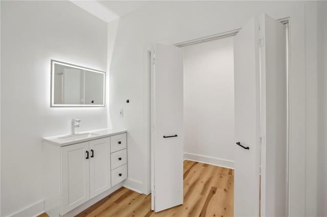 bathroom with wood finished floors, vanity, and baseboards