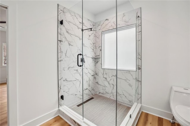 full bathroom featuring a marble finish shower, wood finished floors, toilet, and baseboards