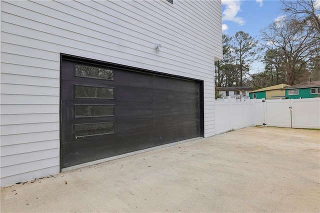 garage featuring driveway, fence, and a gate