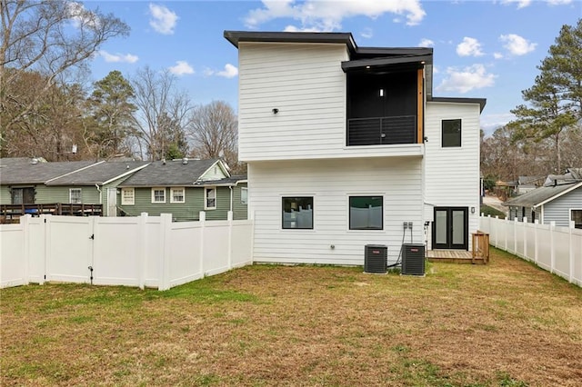 back of property with a fenced backyard, cooling unit, and a lawn