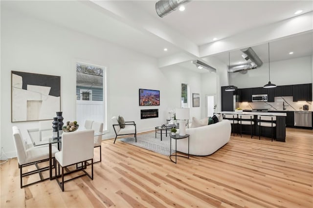 living room with plenty of natural light, light wood-type flooring, and a glass covered fireplace