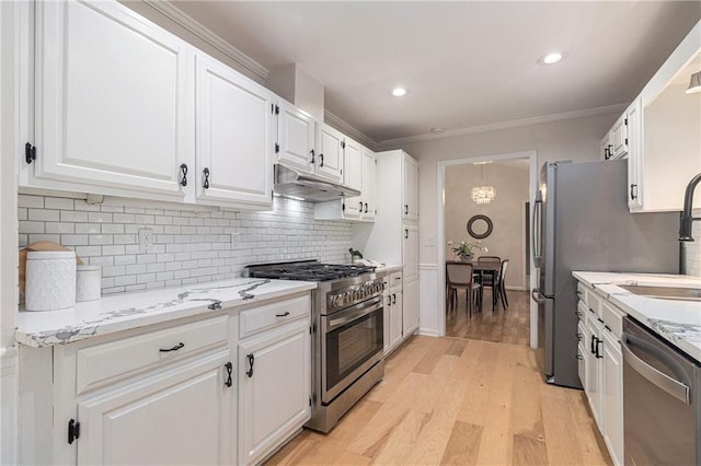 1402 Mclendon Dr, Decatur, GA 30033 - kitchen with appliances with stainless steel finishes, under cabinet range hood, white cabinets, ornamental molding, and light wood finished floors