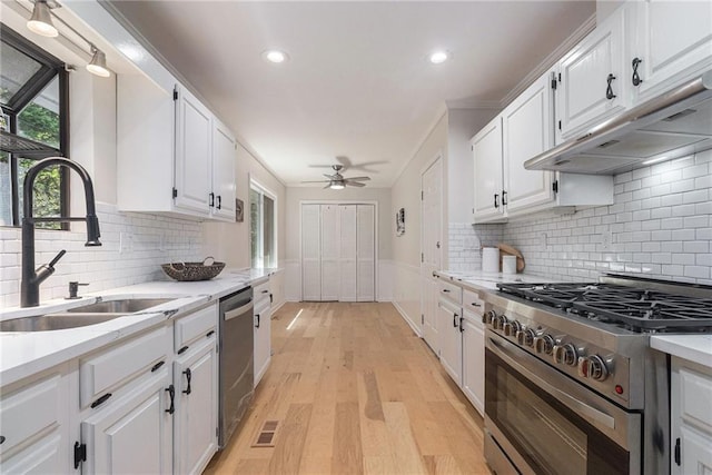 1402 Mclendon Dr, Decatur, GA 30033 - kitchen featuring appliances with stainless steel finishes, under cabinet range hood, white cabinets, light wood-type flooring, and a ceiling fan