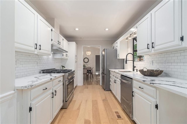 1402 Mclendon Dr, Decatur, GA 30033 - kitchen featuring stainless steel appliances, under cabinet range hood, white cabinets, light wood-type flooring, and tasteful backsplash
