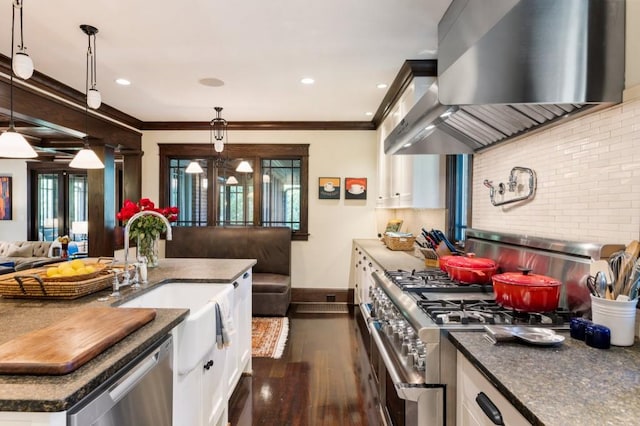 kitchen with stainless steel appliances, pendant lighting, open floor plan, and wall chimney exhaust hood