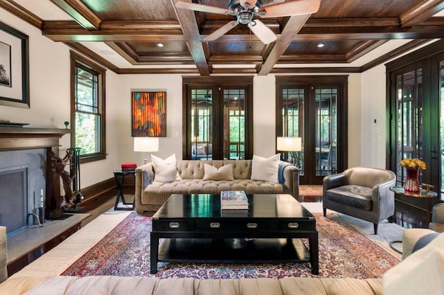 living room with french doors, a fireplace with raised hearth, and crown molding