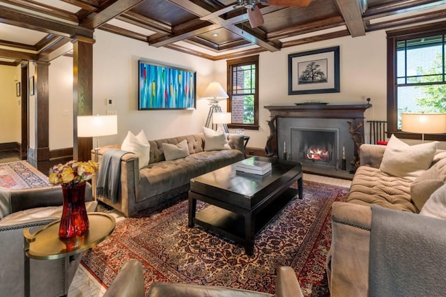 living room with coffered ceiling, a lit fireplace, ornamental molding, beamed ceiling, and decorative columns