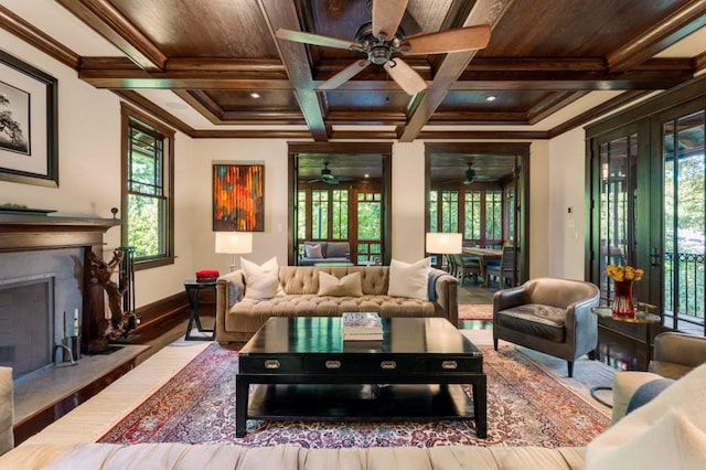 living area featuring beam ceiling, a fireplace with raised hearth, ornamental molding, wooden ceiling, and coffered ceiling