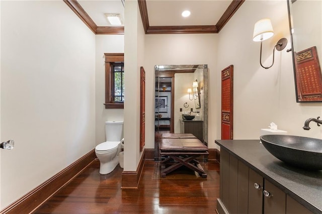 bathroom featuring baseboards, toilet, wood finished floors, crown molding, and vanity