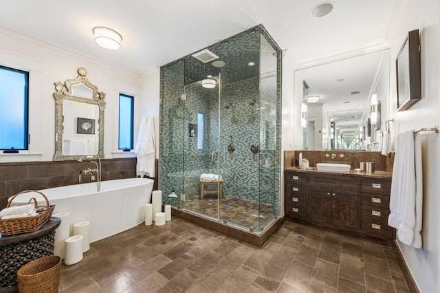 full bathroom featuring tile walls, a freestanding bath, ornamental molding, a stall shower, and vanity