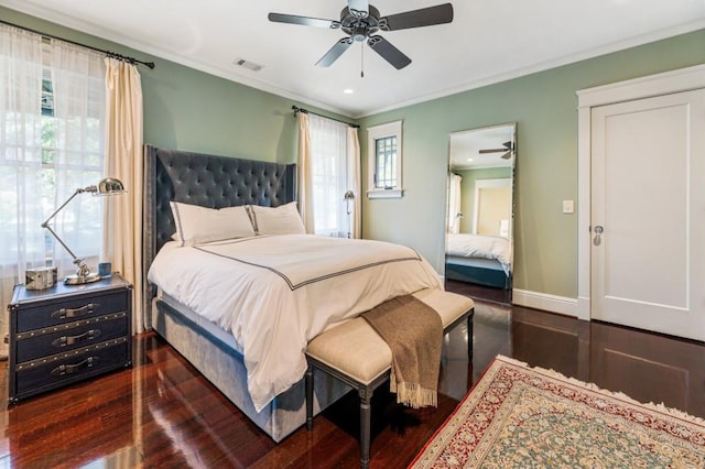 bedroom with crown molding, dark wood finished floors, visible vents, a ceiling fan, and baseboards