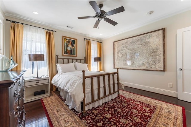 bedroom with dark wood-style floors, visible vents, crown molding, and baseboards