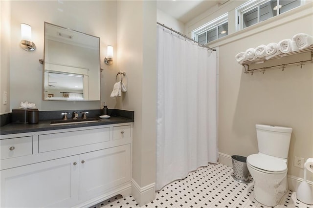 bathroom featuring toilet, a shower with curtain, vanity, and baseboards