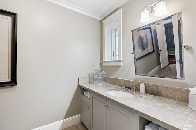 bathroom featuring baseboards, ornamental molding, and vanity