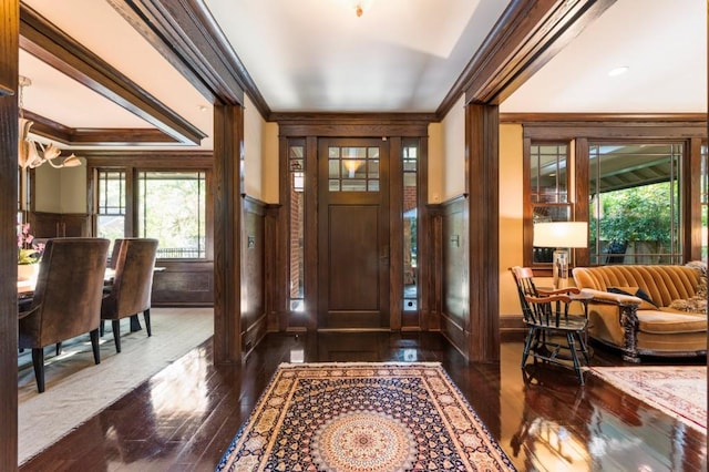 foyer featuring a wainscoted wall, dark wood-style flooring, and crown molding