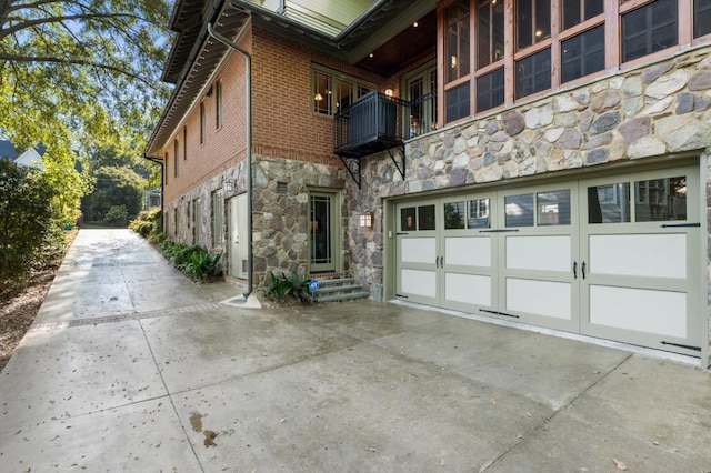 view of side of property featuring stone siding, brick siding, and driveway