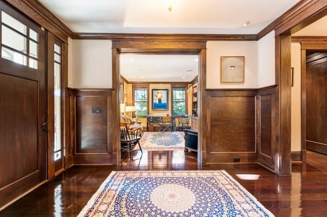 foyer featuring a wainscoted wall, a decorative wall, and crown molding