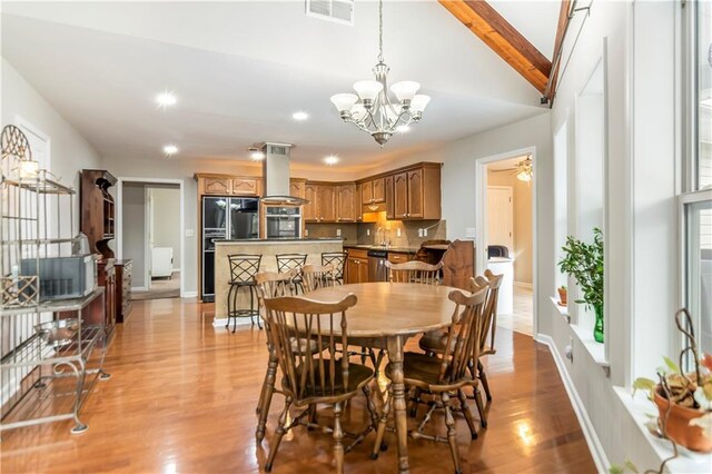 kitchen featuring dark stone countertops, light hardwood / wood-style floors, a kitchen bar, appliances with stainless steel finishes, and island range hood