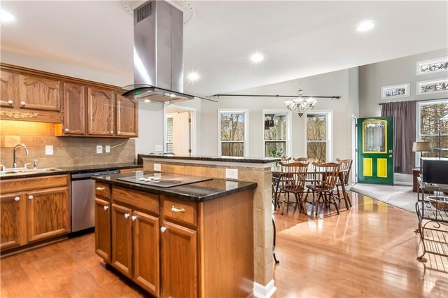 kitchen with light wood-type flooring, island range hood, dark stone countertops, and a center island