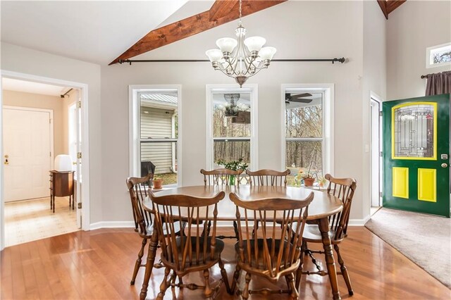 dining space with a notable chandelier, hardwood / wood-style floors, high vaulted ceiling, and beamed ceiling