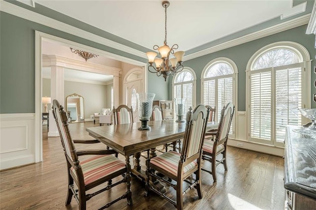 dining room with a chandelier, a wainscoted wall, a wealth of natural light, and wood finished floors