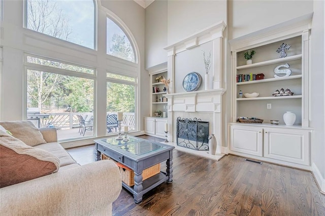 living room featuring visible vents, plenty of natural light, a towering ceiling, and dark wood-style flooring