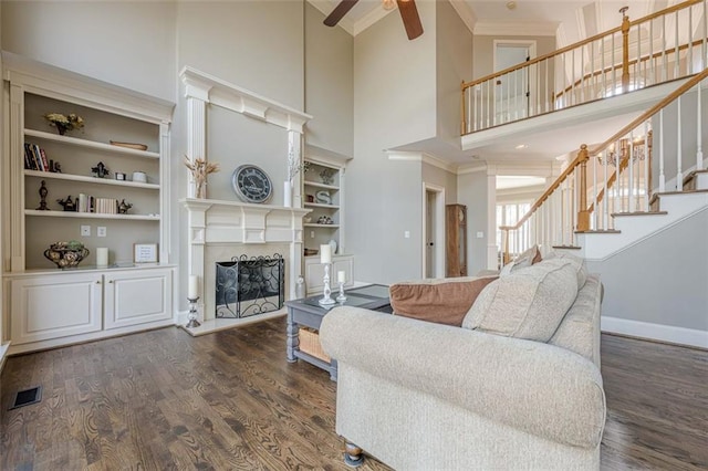 living area featuring stairway, wood finished floors, visible vents, and a fireplace with raised hearth