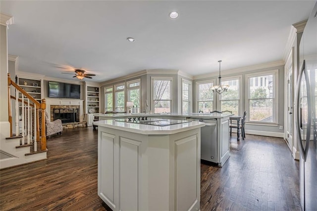 kitchen with a kitchen island, stainless steel appliances, crown molding, a fireplace, and light countertops