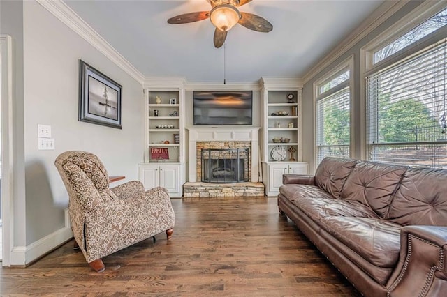 living room featuring wood finished floors, a ceiling fan, baseboards, a fireplace, and crown molding