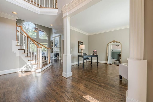 foyer entrance featuring decorative columns, baseboards, wood finished floors, and stairway