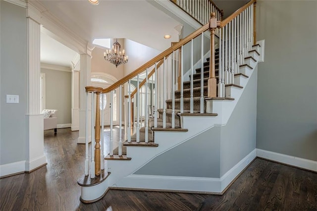 stairway featuring decorative columns, baseboards, wood finished floors, and crown molding