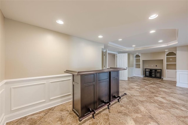 kitchen with built in features, a tray ceiling, wainscoting, recessed lighting, and a decorative wall