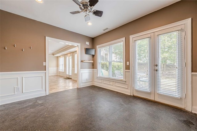 empty room with visible vents, french doors, a ceiling fan, and a wainscoted wall