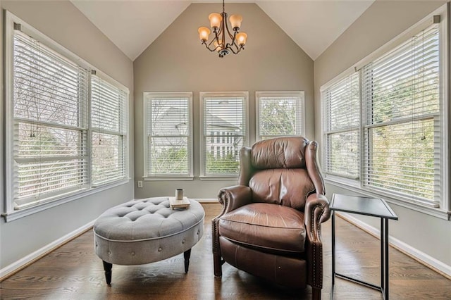 sitting room featuring a wealth of natural light, vaulted ceiling, an inviting chandelier, and wood finished floors