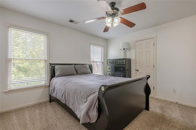 bedroom featuring visible vents, light colored carpet, a ceiling fan, and baseboards