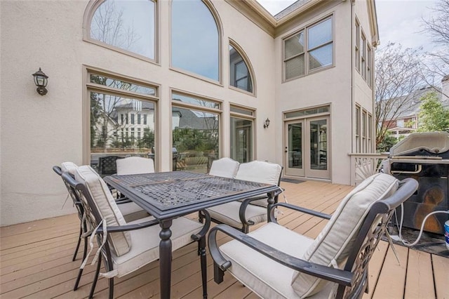 wooden deck featuring outdoor dining area, french doors, and grilling area