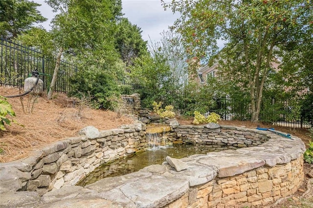 view of yard featuring a garden pond and fence