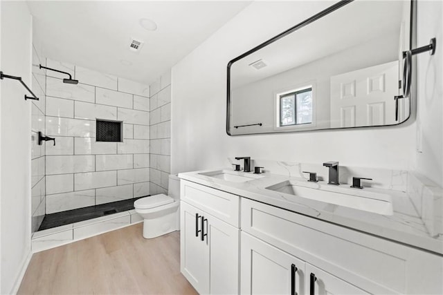 bathroom featuring visible vents, double vanity, a sink, and toilet