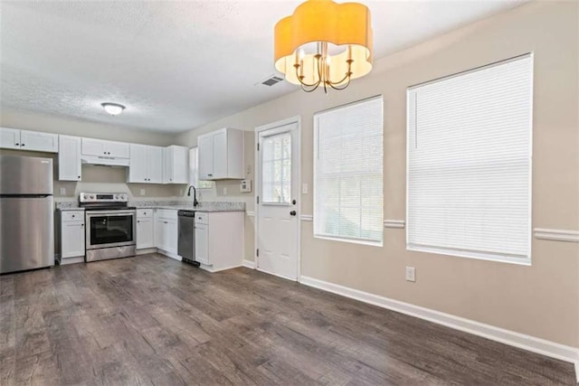 kitchen with appliances with stainless steel finishes, dark hardwood / wood-style flooring, sink, white cabinets, and a chandelier