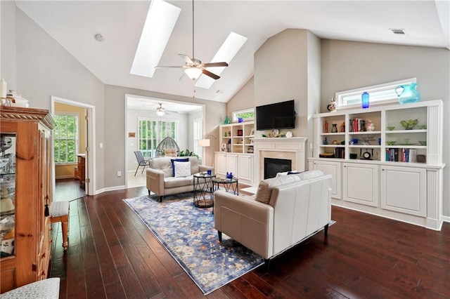 living room featuring ceiling fan, dark wood-type flooring, high vaulted ceiling, and a skylight