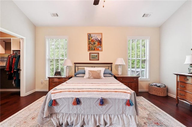 bedroom with ceiling fan, a spacious closet, dark hardwood / wood-style flooring, and a closet