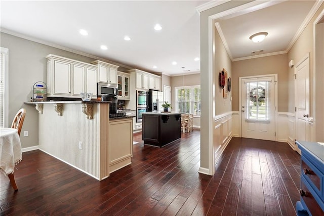 kitchen featuring dark wood-type flooring, appliances with stainless steel finishes, kitchen peninsula, and a breakfast bar area