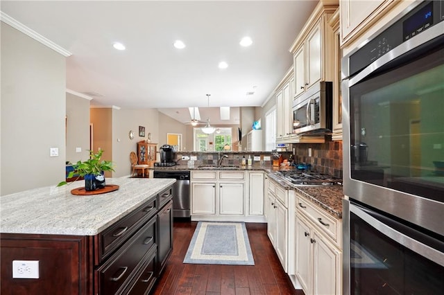 kitchen featuring pendant lighting, appliances with stainless steel finishes, tasteful backsplash, dark hardwood / wood-style flooring, and kitchen peninsula