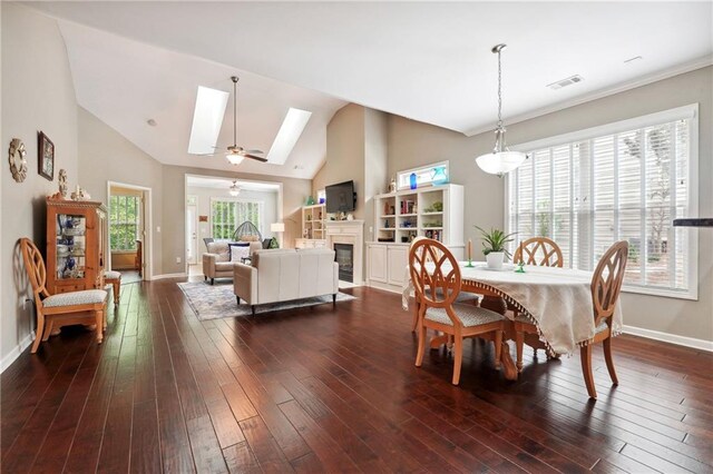 dining area featuring dark hardwood / wood-style floors and vaulted ceiling with skylight