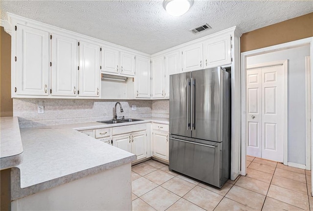 55 Ashland Farm Rd, Oxford, GA 30054 - kitchen featuring freestanding refrigerator, light countertops, light tile patterned floors, white cabinetry, and a textured ceiling