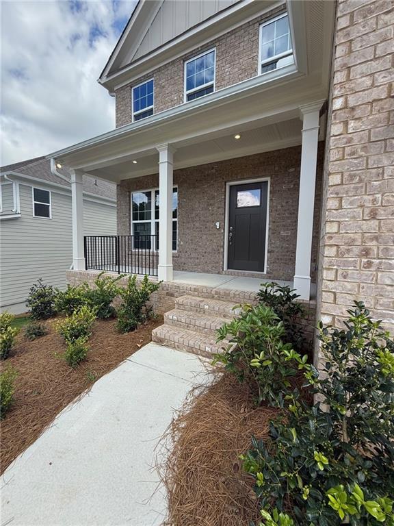 4266 Mulberry Pass Ct, Hoschton, GA 30548 - view of exterior entry with brick siding, board and batten siding, and a porch