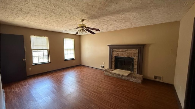 unfurnished living room featuring visible vents, a fireplace, wood finished floors, and a ceiling fan