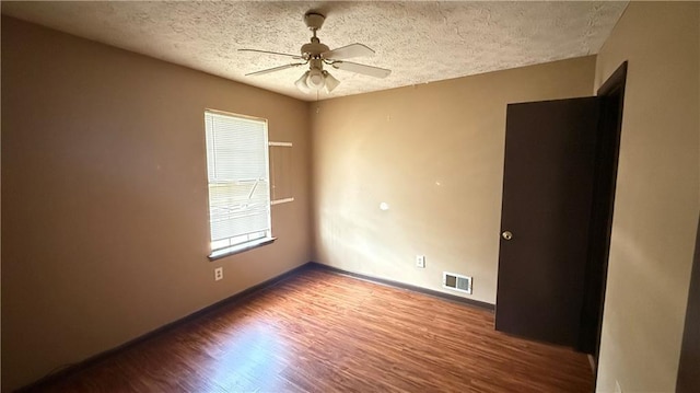 unfurnished room with a ceiling fan, baseboards, wood finished floors, visible vents, and a textured ceiling